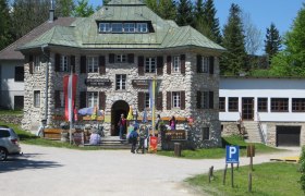 Alpine and local history museum Hohe Wand with visitors and flags in front of the entrance.