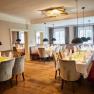 Elegant restaurant with set tables, upholstered benches and hanging lamps at Schloss Luberegg