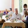 A restaurant with guests sitting at tables and being served by a waitress.