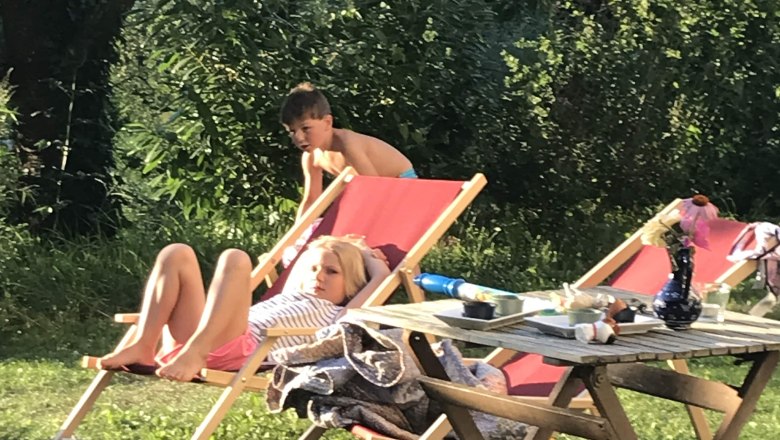 Two children relax on sun loungers in the garden.
