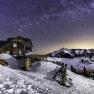 Mountain hut in the snow under a clear starry sky.