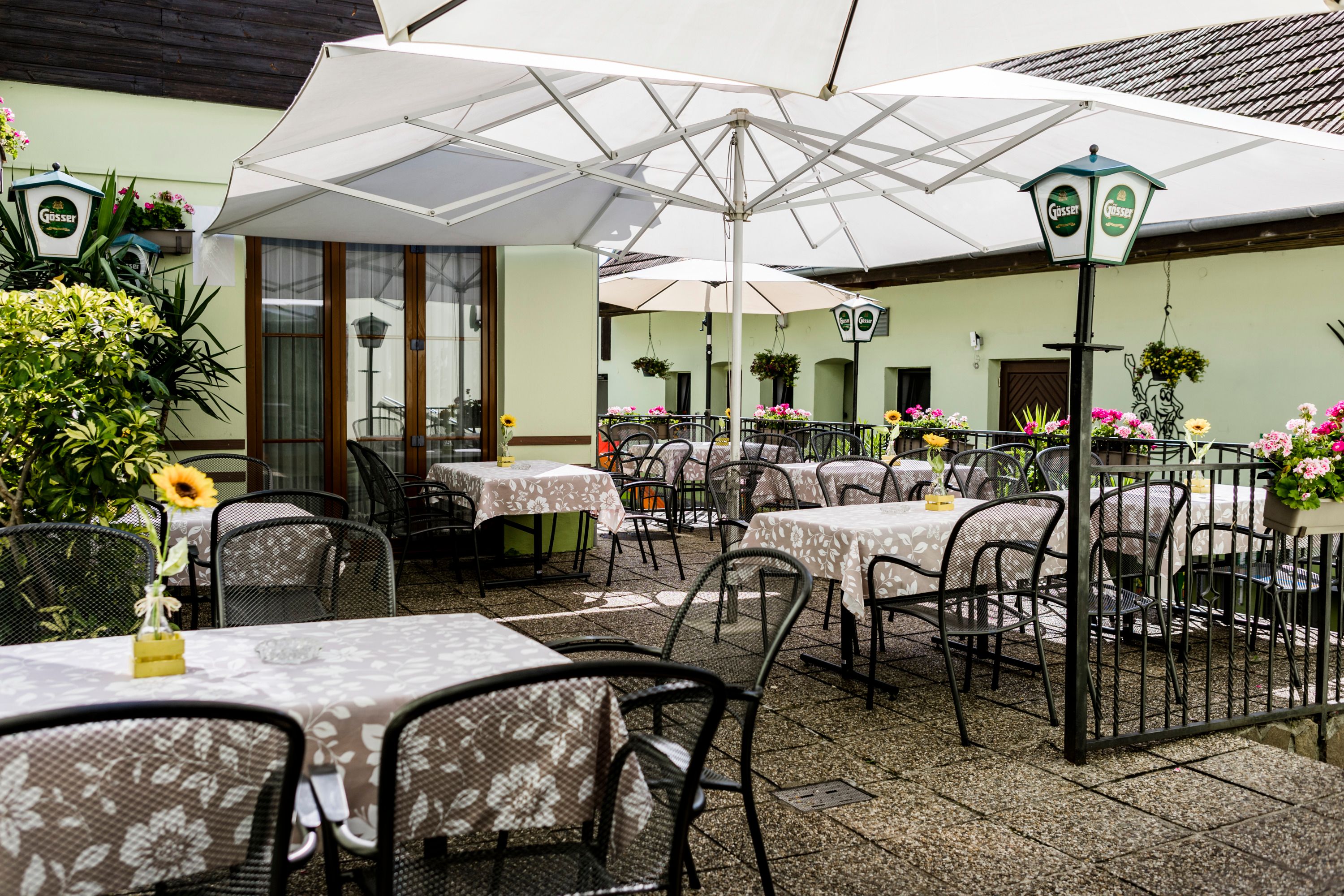 Comfortable terrace with tables, chairs and parasols, decorated with flowers.