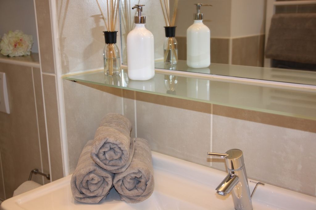 Bathroom with towels, soap dispenser and fragrance sticks.
