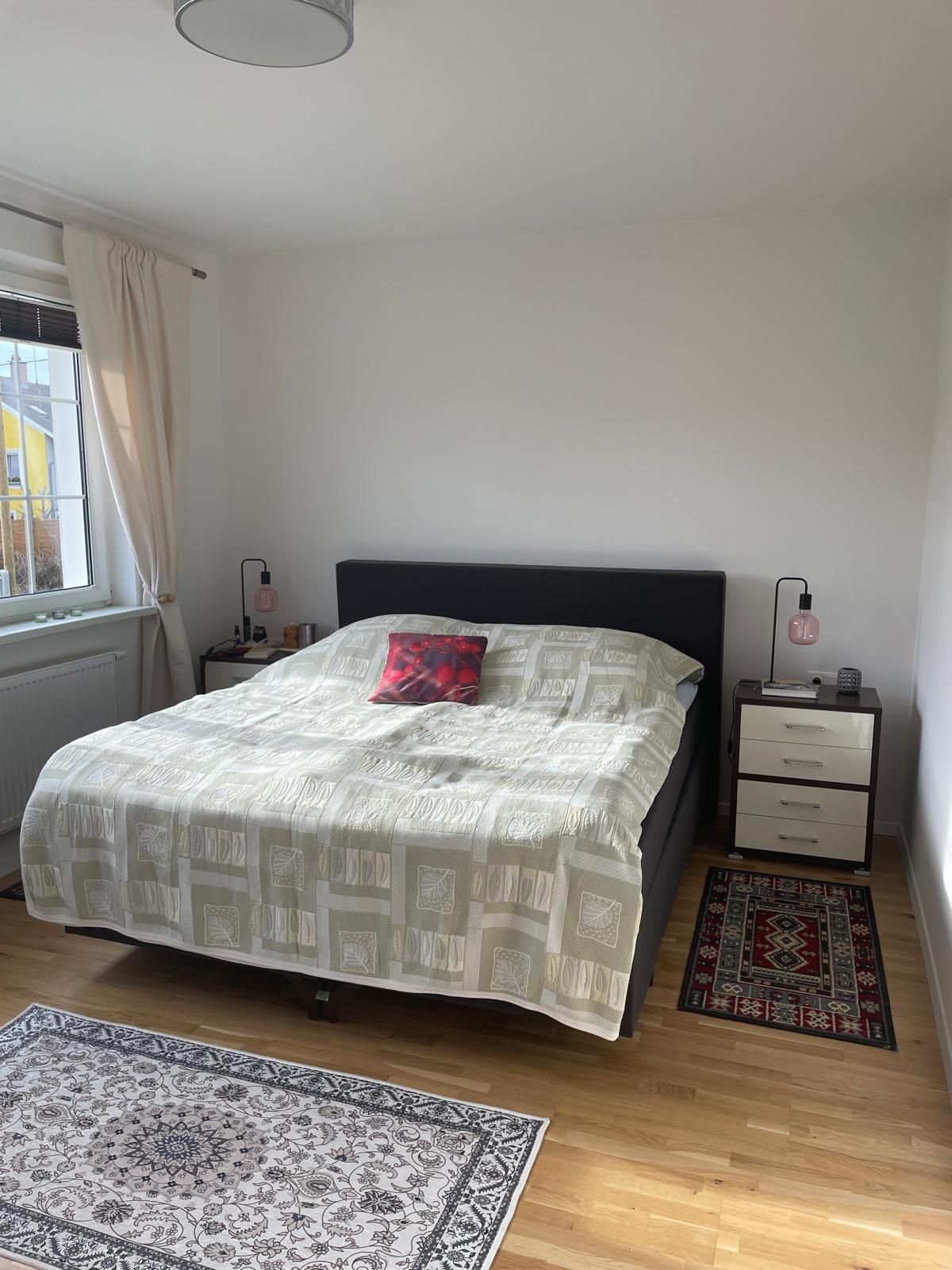 One bedroom with a double bed, two bedside tables and carpets on a wooden floor.