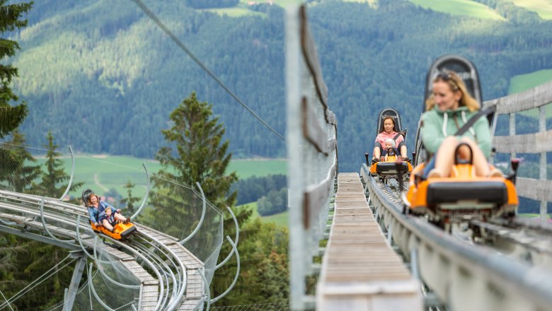 People ride on a summer toboggan run in the mountains.
