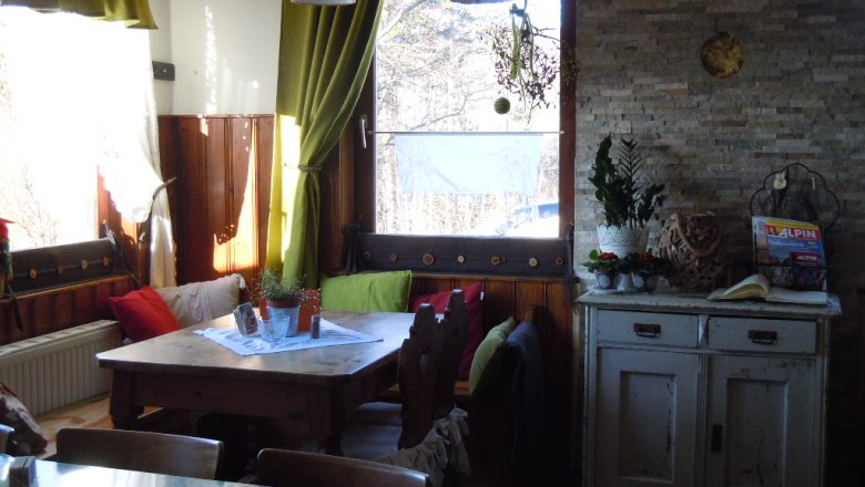 Cozy corner in a room with wooden table, cushions and plants.