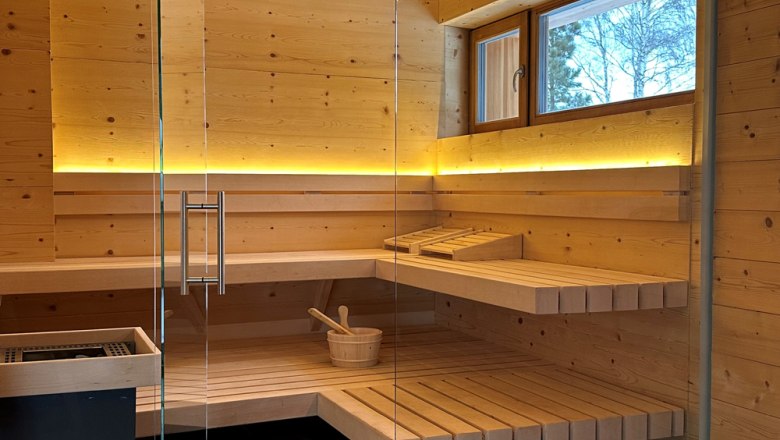 Interior view of a modern sauna with wooden benches and glass wall.