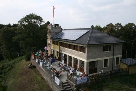 Höllensteinhaus with terrace and solar panels on the roof, surrounded by trees.