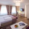 Elegant hotel room with double bed, desk, TV and fruit plate.