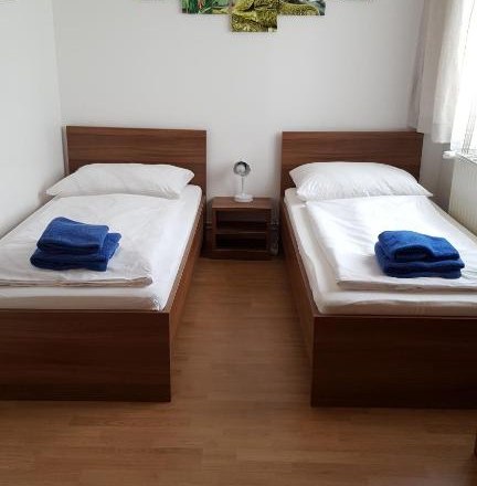 Double room, © Haus Nova Two single beds in a room with wall decoration and blue towels.