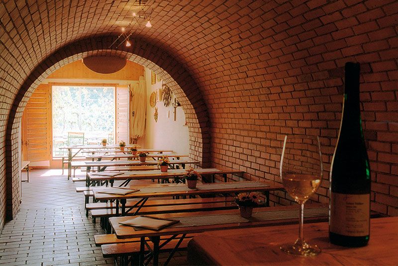 Wine cellar with brick vaults, wooden tables and wine bottles.