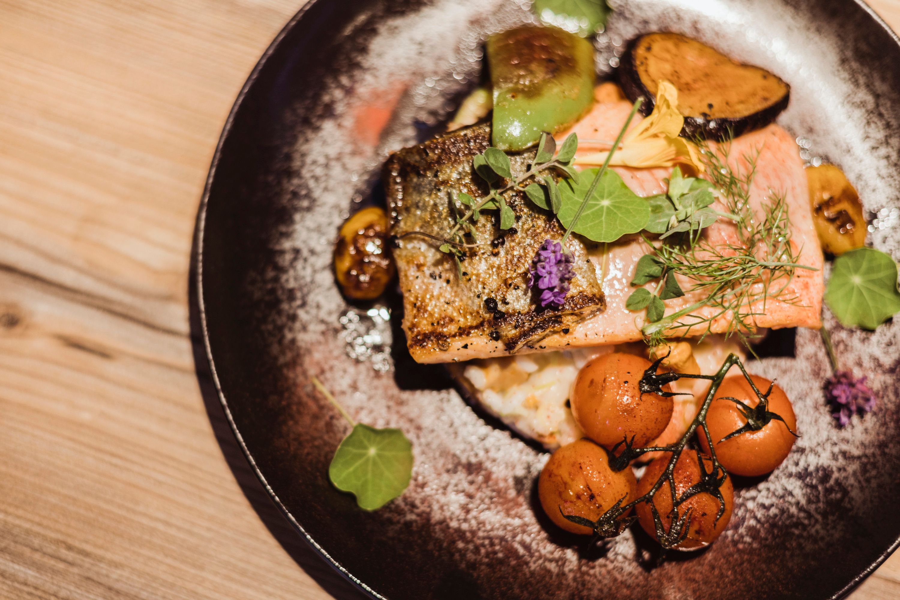 Salmon trout fillet on grammel risotto with vegetables and herbs on a plate.