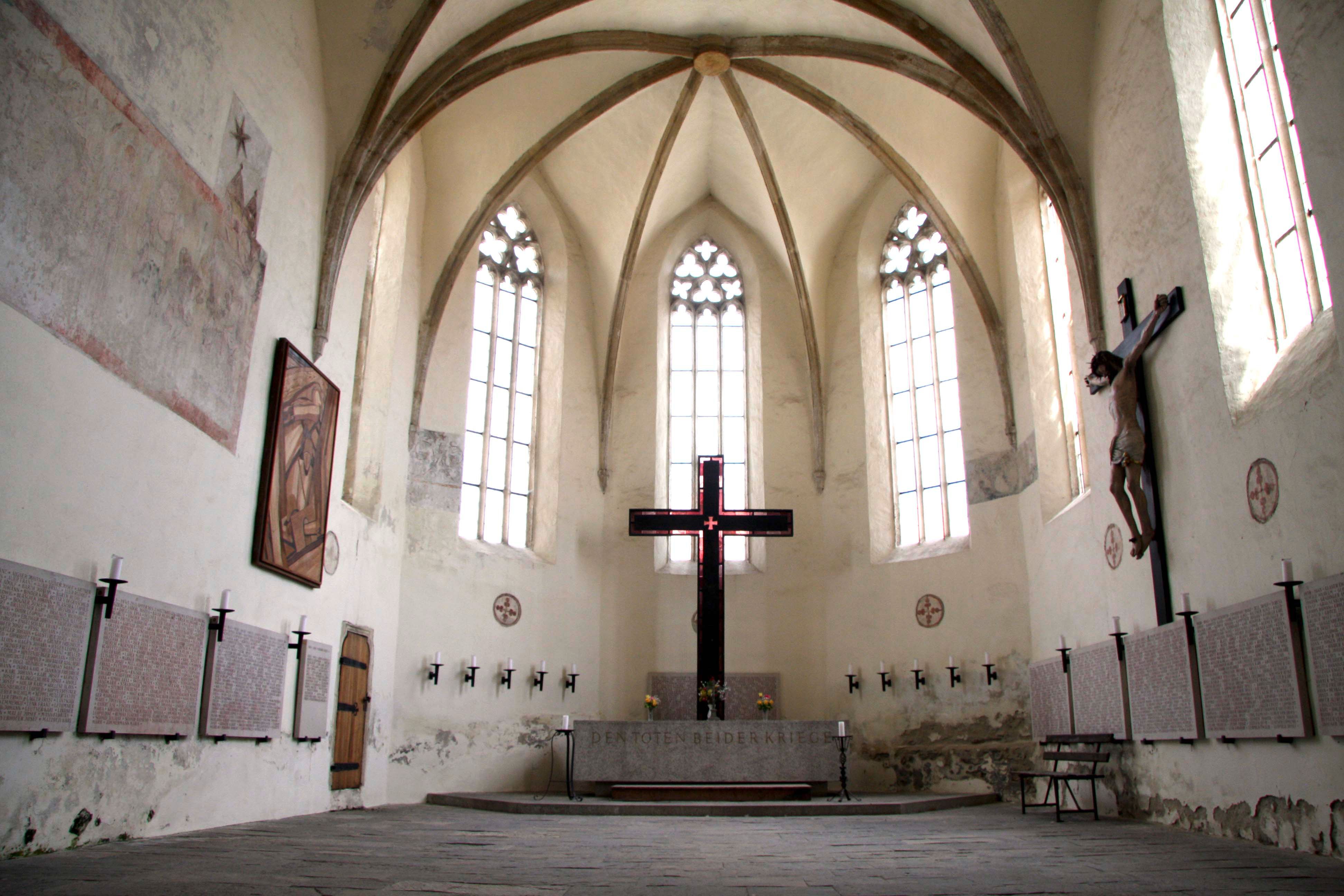Interior view of the Frauenbergkirche Stein with Gothic windows and a large cross.
