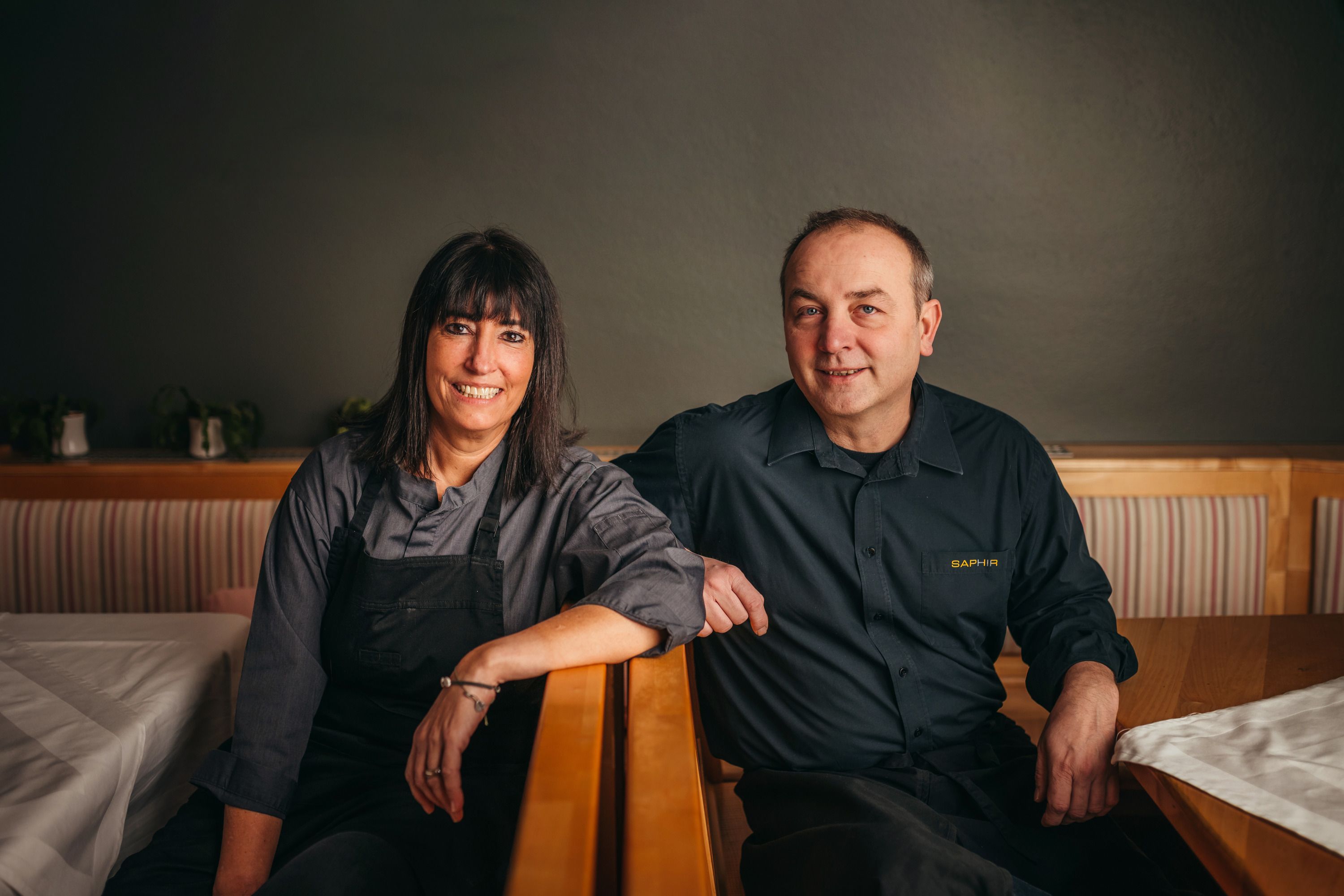 Two people in work clothes sit smiling in a restaurant.