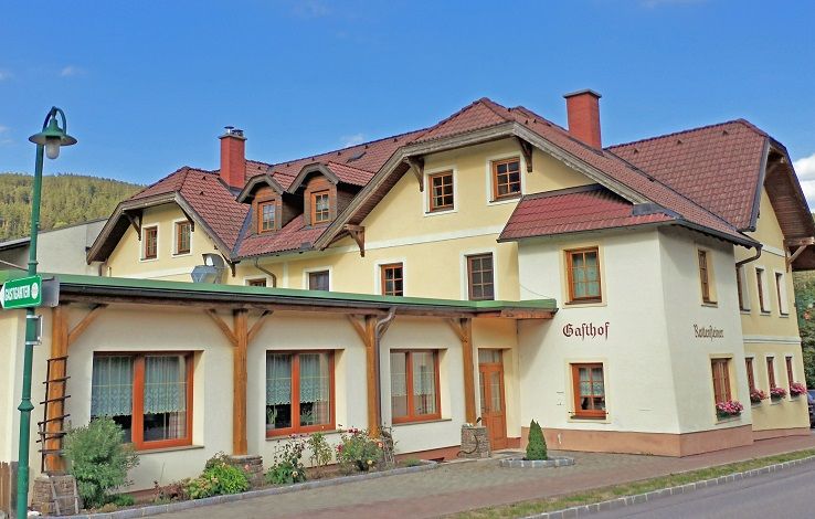 A traditional inn with a yellow façade and red roofs.