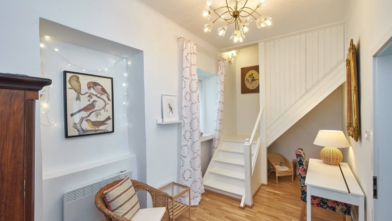 Living area with staircase, rattan furniture and bird pictures on the wall.