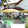 A cozy garden with green tables and chairs under yellow parasols in front of a building.