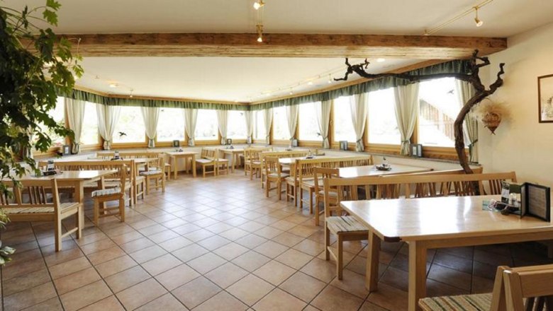 Interior view of a wine tavern with wooden furniture and large windows.
