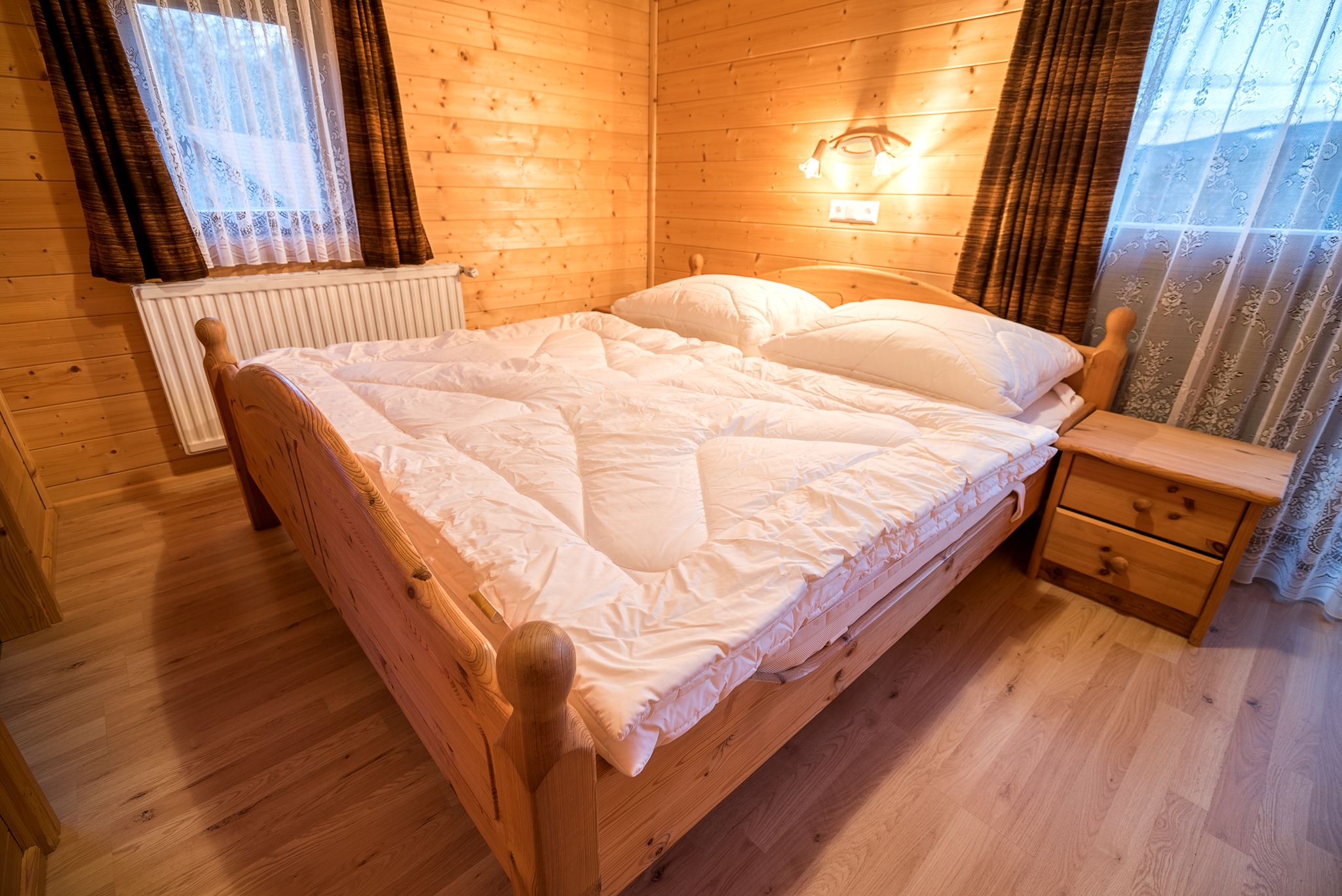 Cozy bedroom with wooden walls, double bed and bedside table in a vacation apartment.
