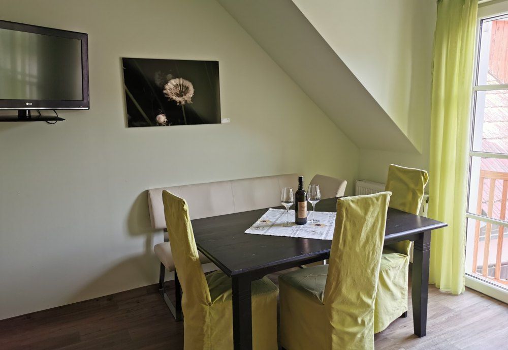 Dining area in a vacation apartment with table, chairs and bottle of wine.