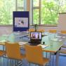 A seminar room with table, chairs, laptop, flipchart and pin board.