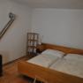 A simply furnished bedroom with double bed, bedside tables, shelf and stove.