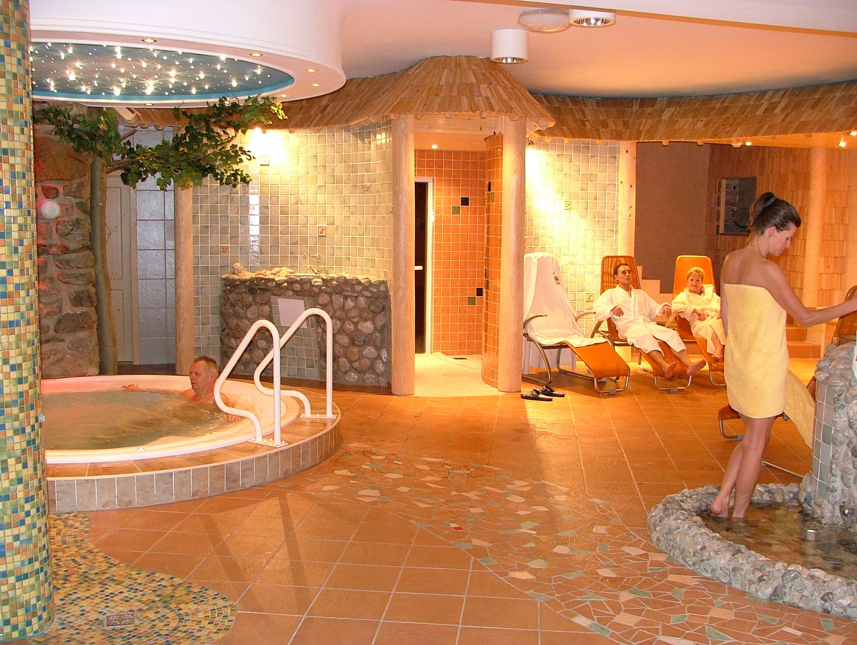 A wellness area with whirlpool, loungers and people in bathrobes.