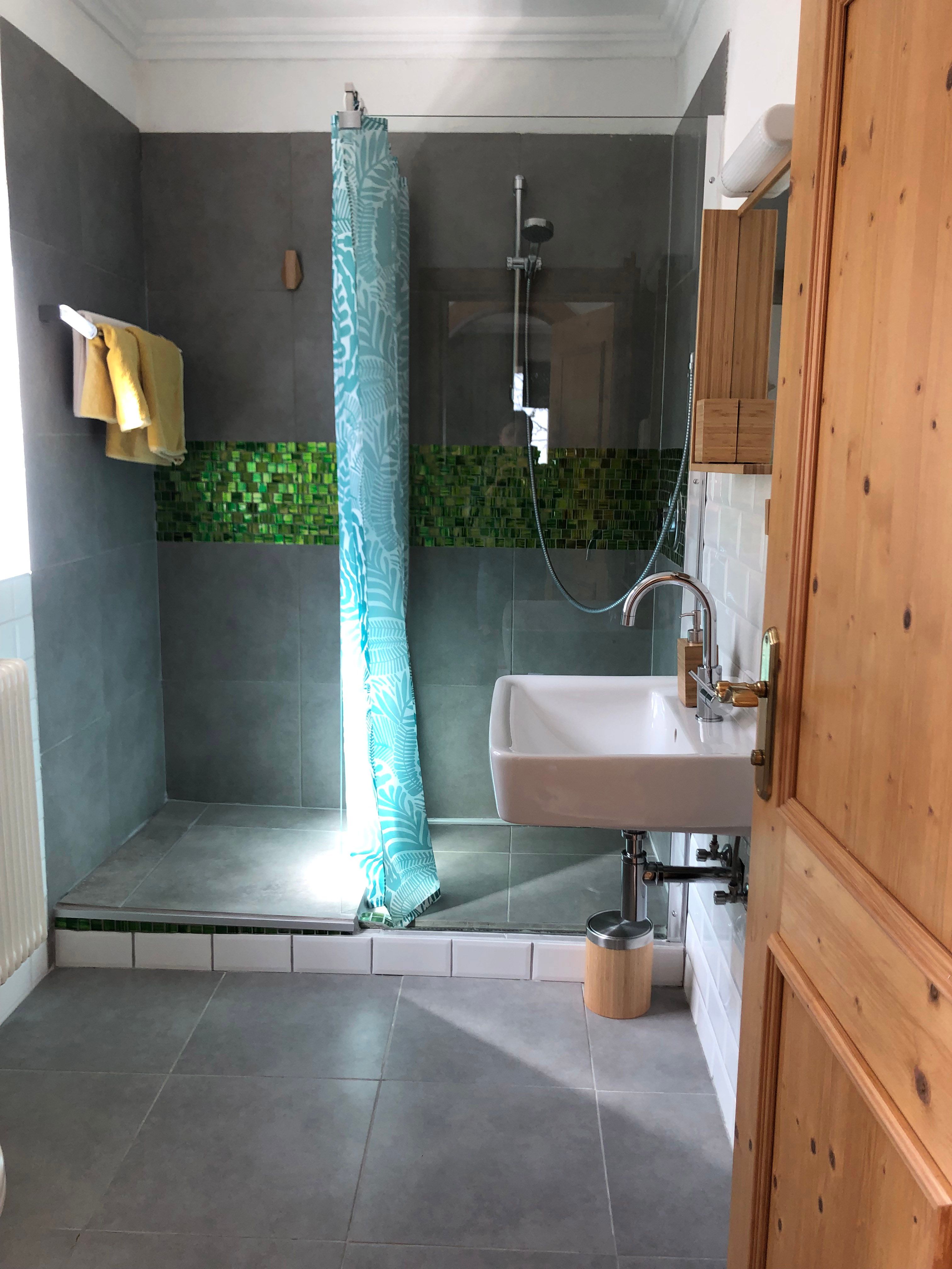 Modern bathroom with shower, washbasin and blue shower curtain.