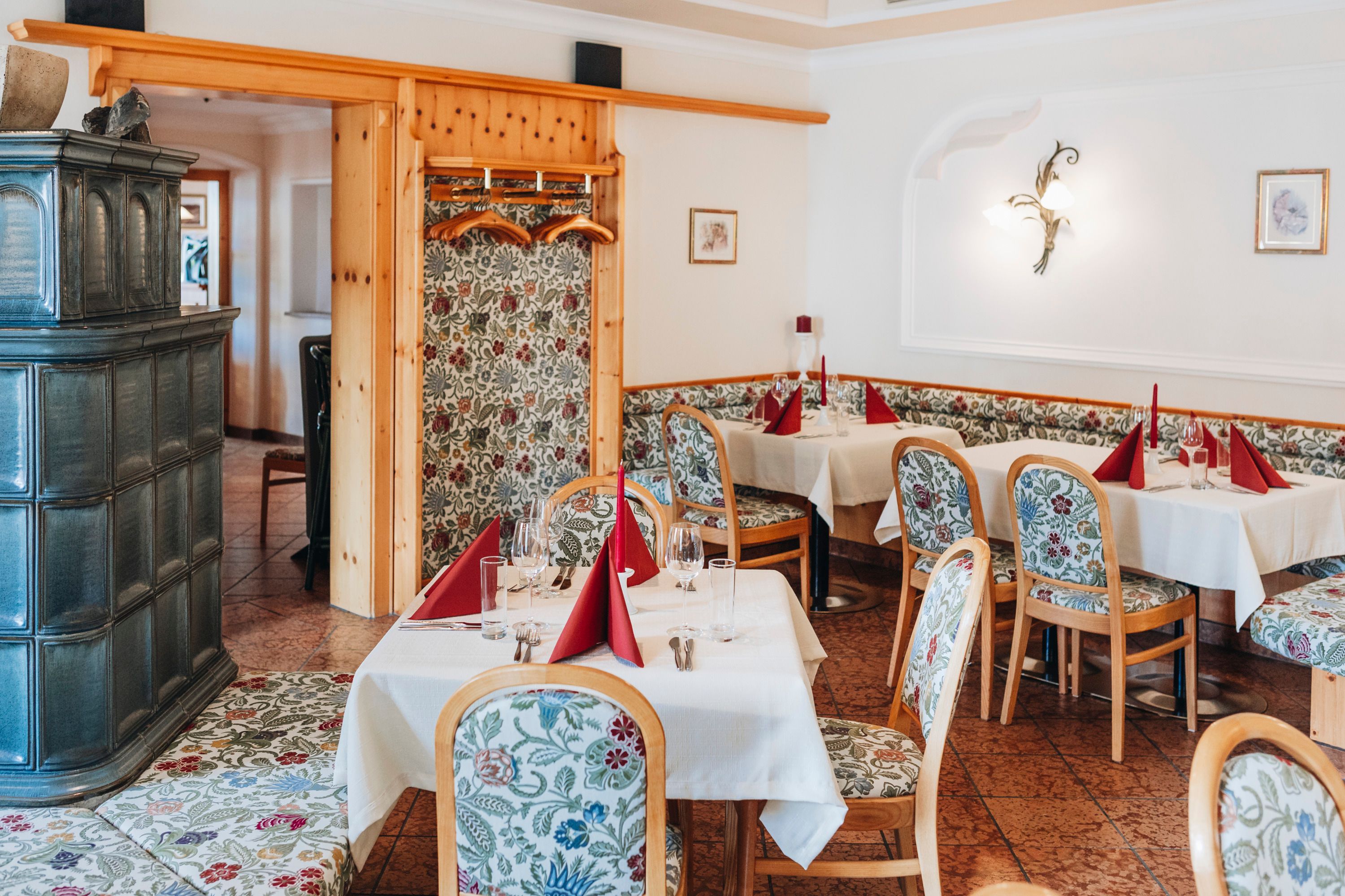 Cozy pub with laid tables and floral patterned chairs.