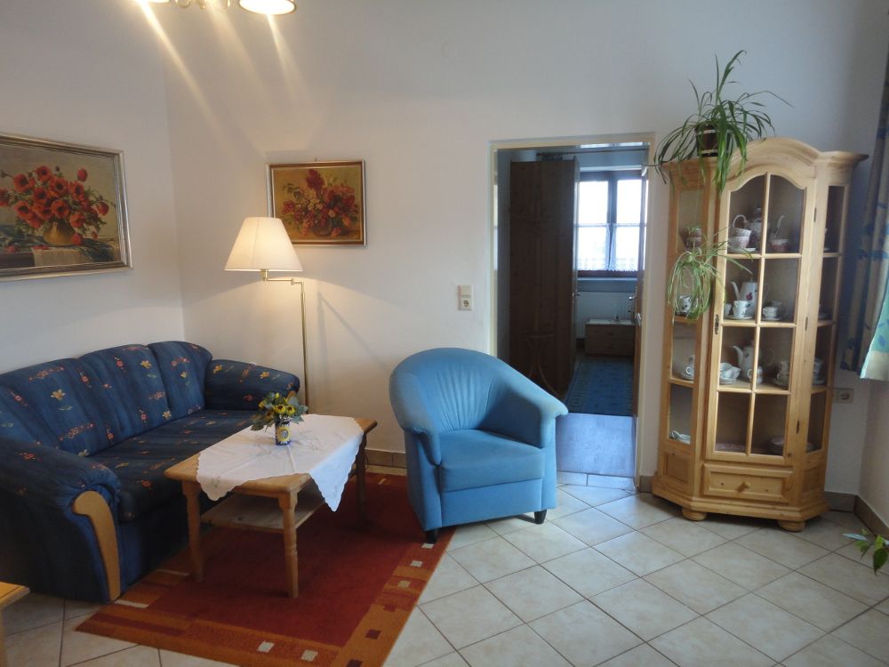 Living room with blue couch, blue armchair, wooden table and display cabinet.