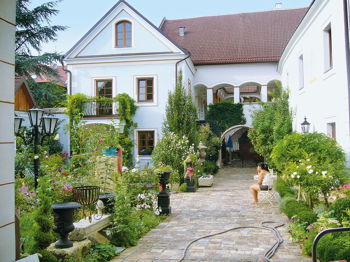 An idyllic courtyard with plants and a seated person.