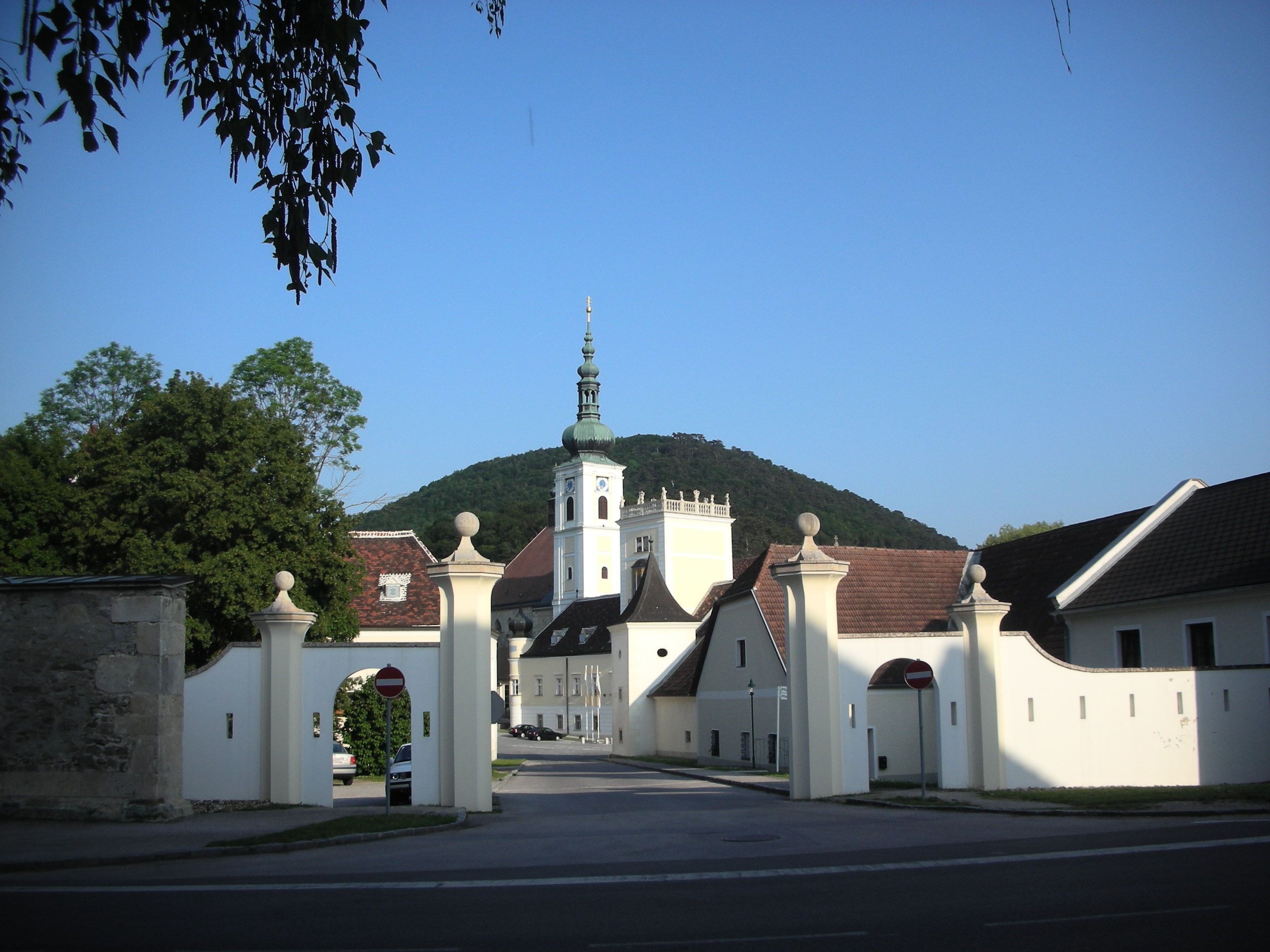 Entrance gate of Heiligenkreuz Abbey with church tower in the background.