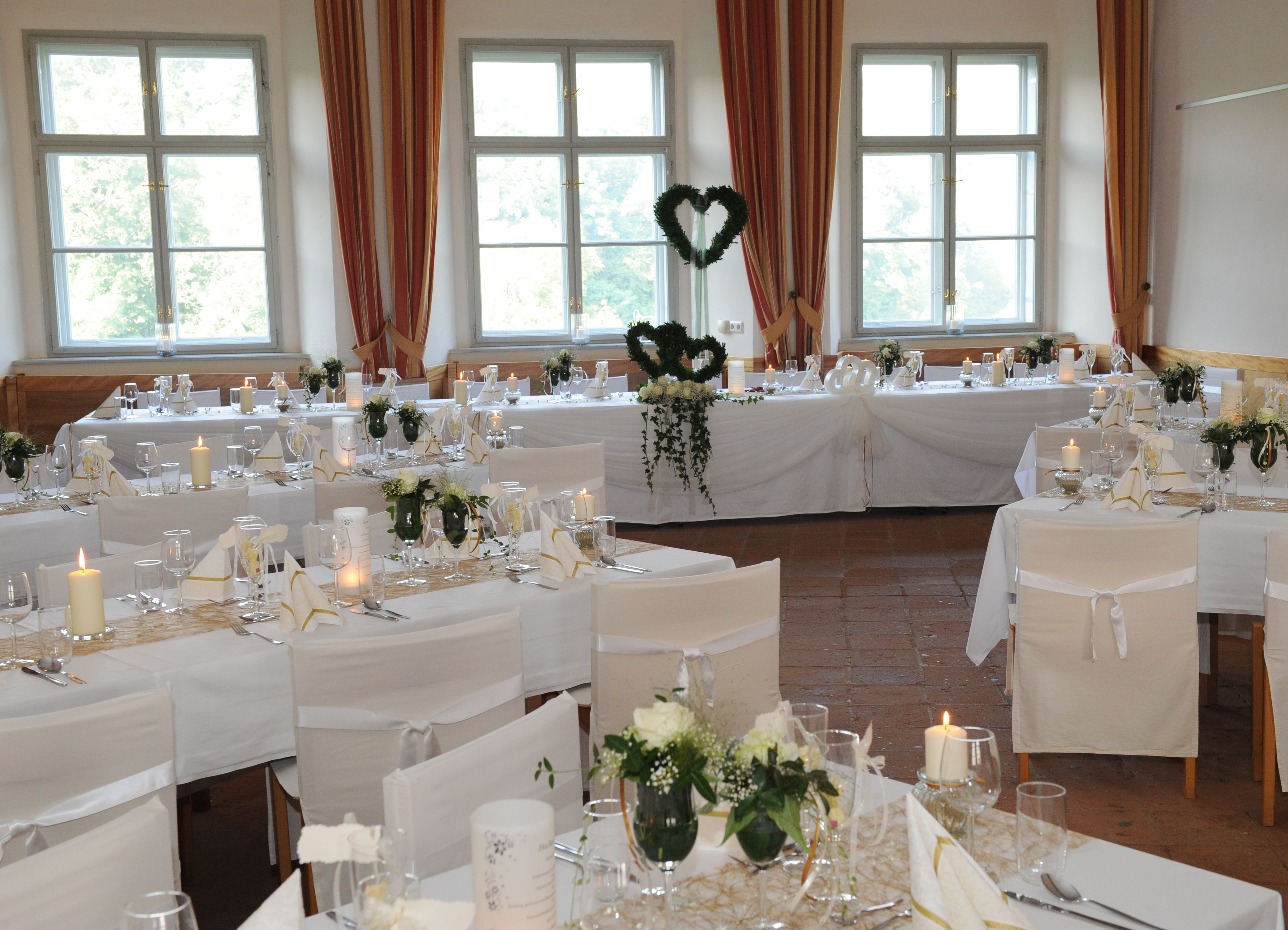 Elegant ballroom with laid tables, white chair covers and candles.