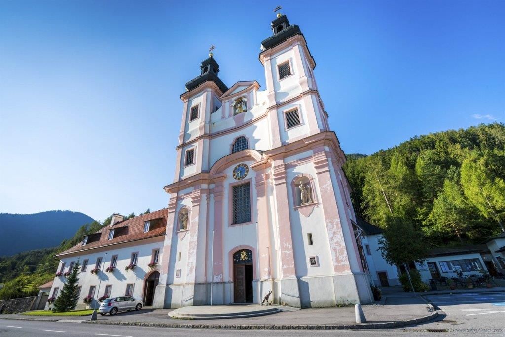 Maria Schutz pilgrimage church with blue sky and green trees in the background.