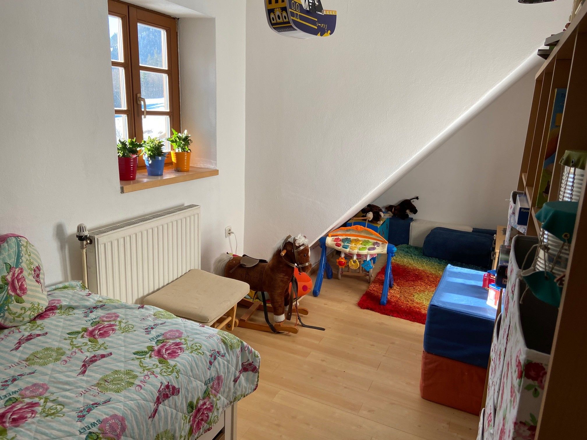 Children's room with bed, toys and colorful carpet.