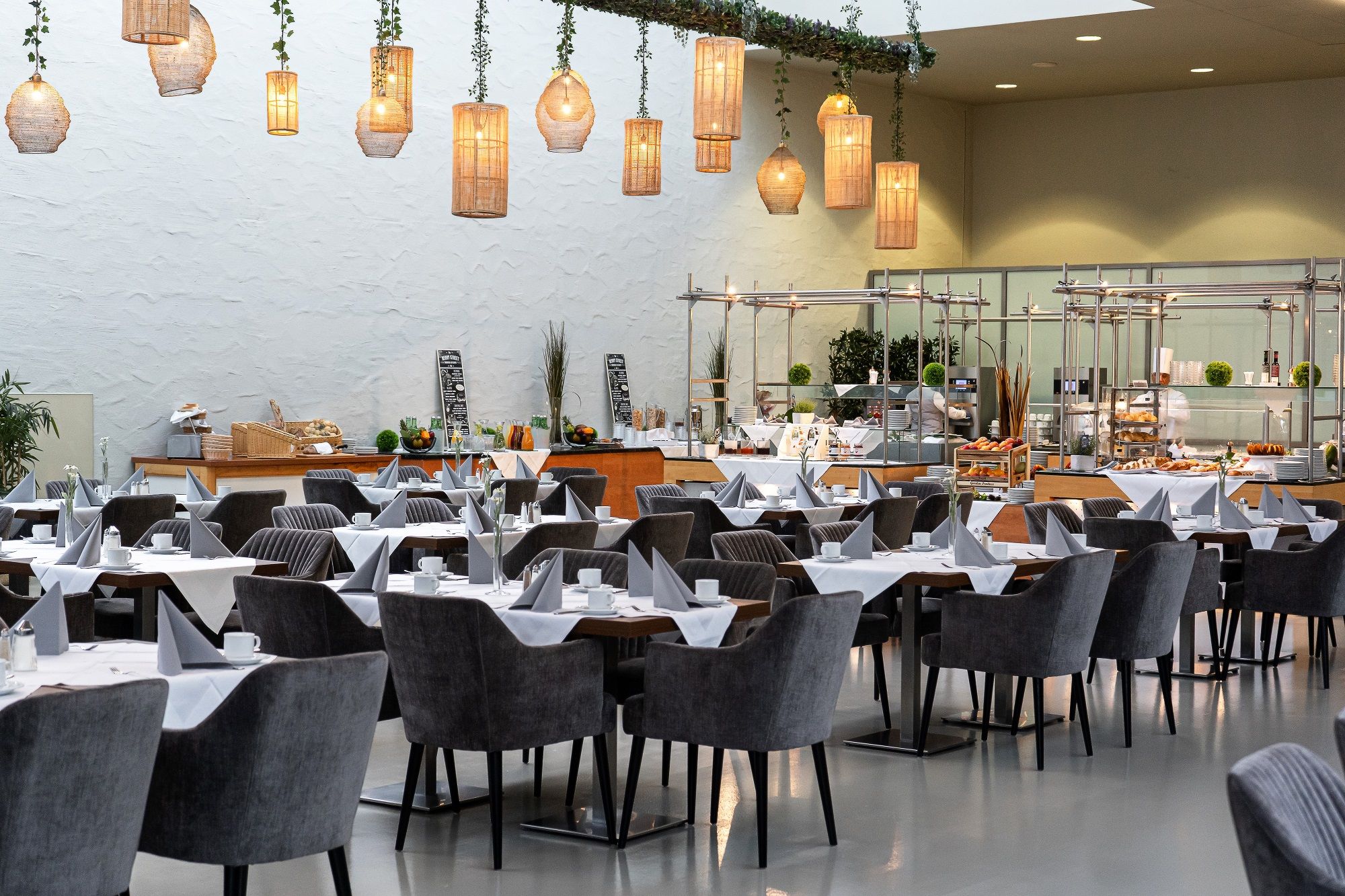 Interior view of a stylish restaurant with laid tables and hanging lamps.