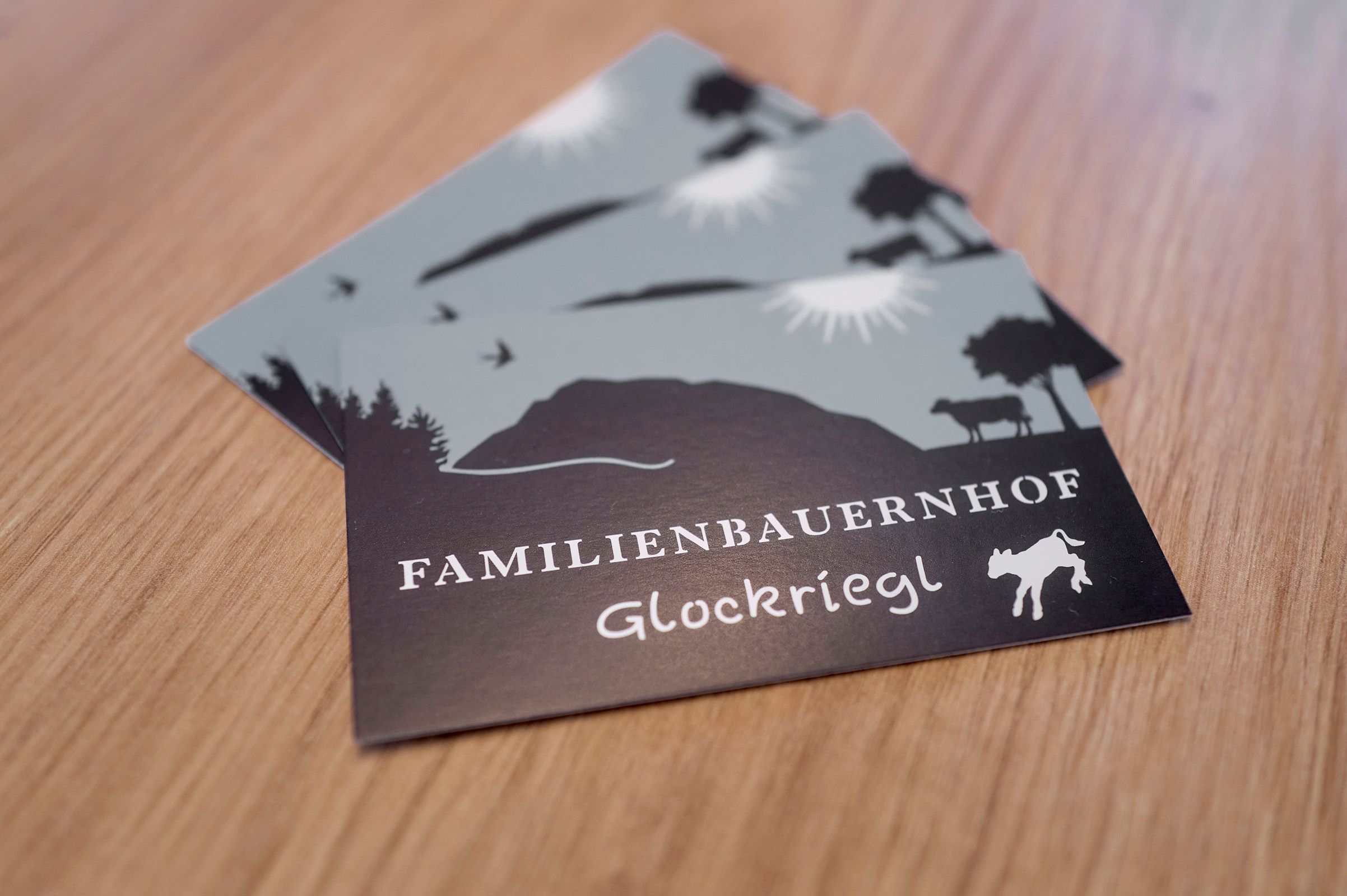 Postcards with the logo of the Glockriegl family farm on a wooden table.