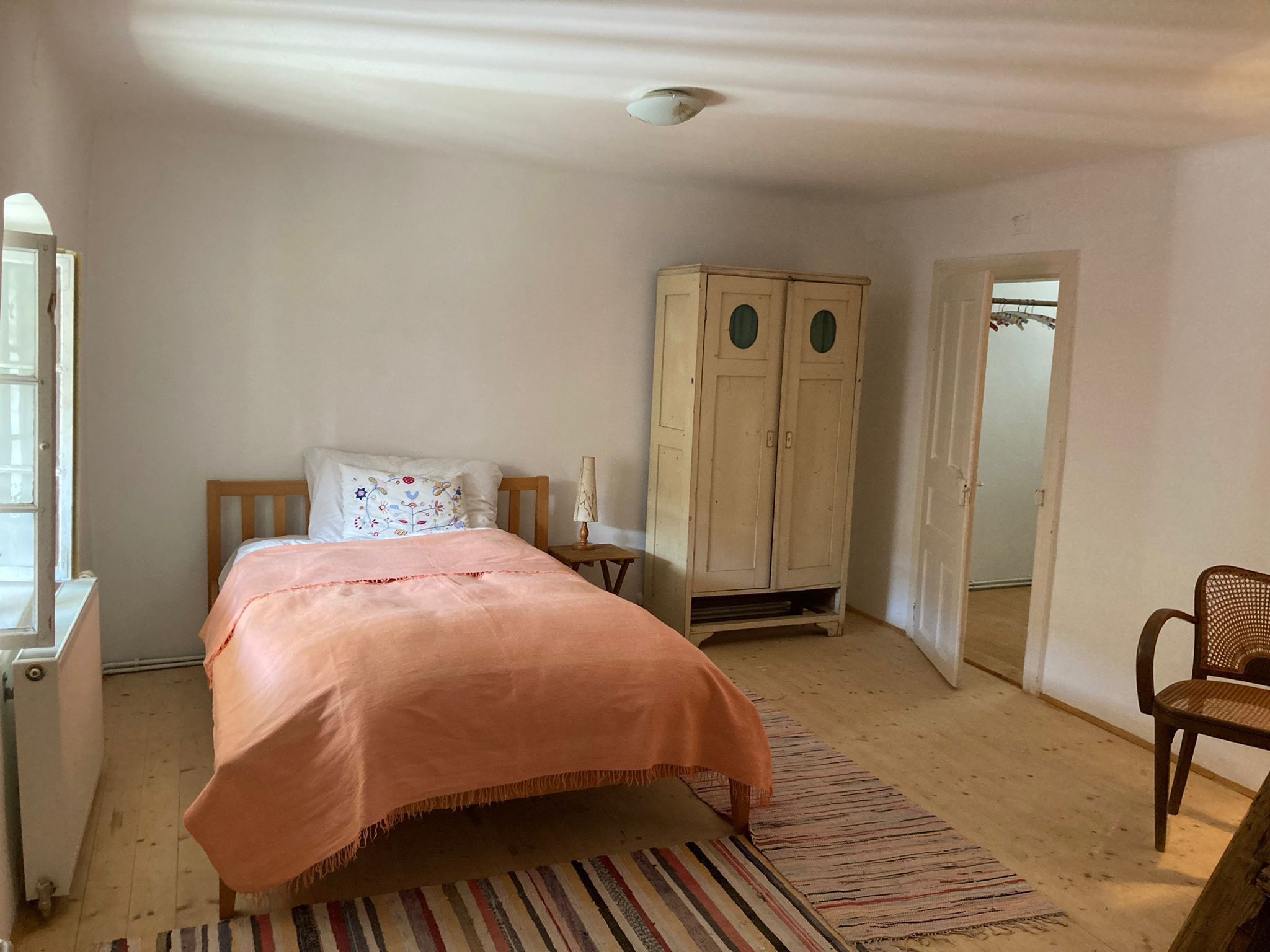 Bed with orange bed linen, an old wardrobe and an old door.