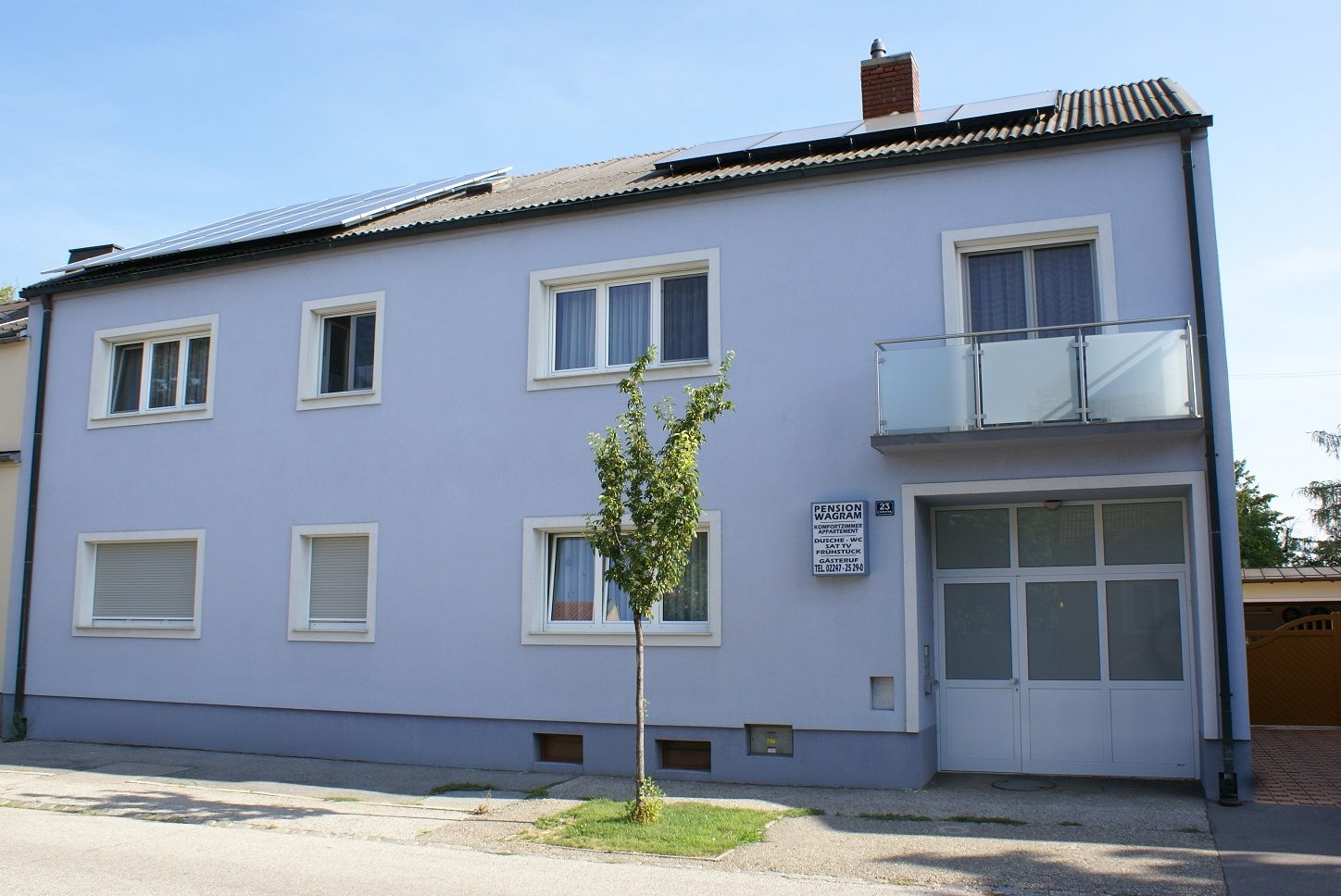 Exterior view of a two-storey building with a blue façade and solar panels on the roof.