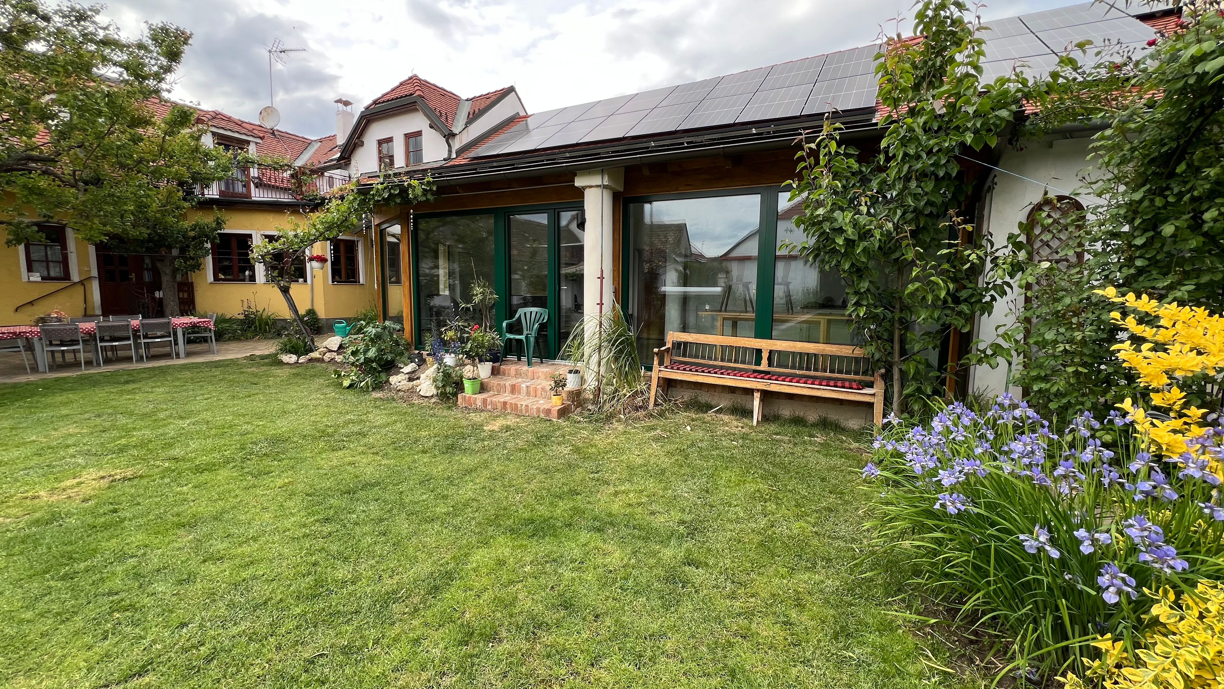 A garden with a lawn, flower beds and a house with solar panels on the roof.