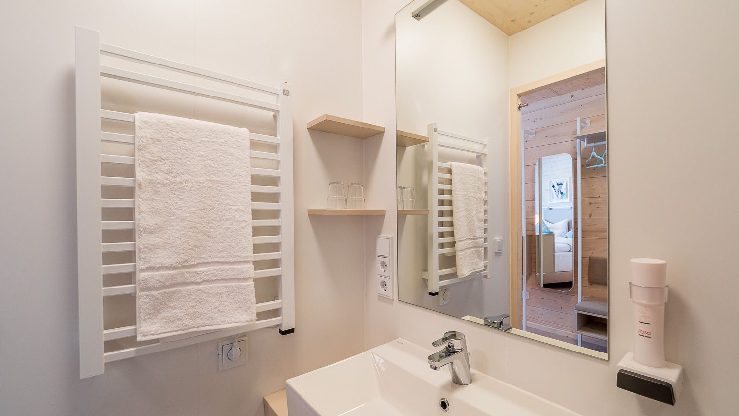 Modern bathroom with towel rail, mirror and washbasin.