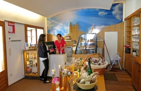 Interior view of a visitor center with two women at the counter and various products on a table.