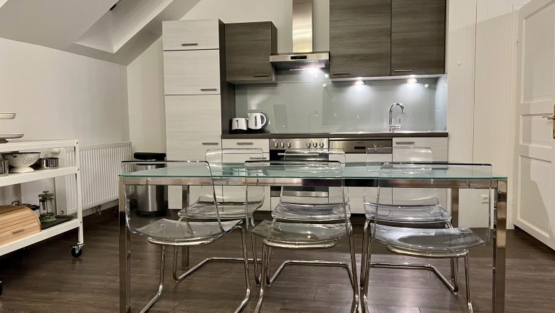 Modern kitchen with glass dining table and transparent chairs in a loft.