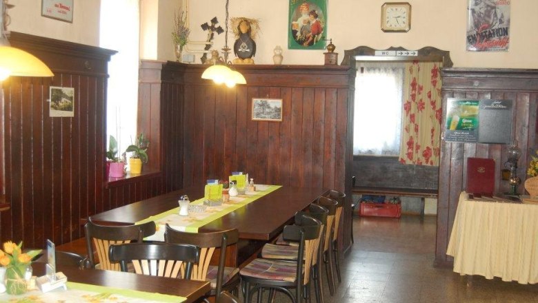 Cozy guest room with wood paneling, table with chairs, decorative posters and a clock on the wall.