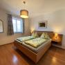 Bedroom with double bed, wooden floor, bedside tables and lamp.