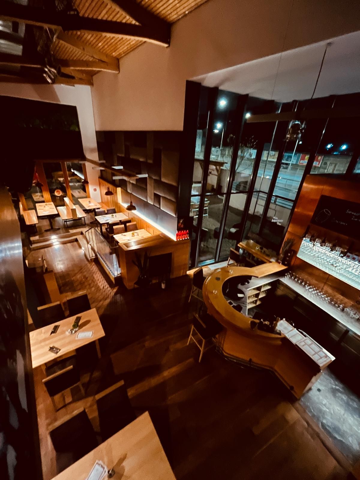 Interior view of Brauhaus Schwechat at night with wooden tables and a bar.
