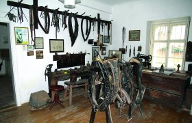 A room in a local history museum with old tools and horse harnesses on the walls.