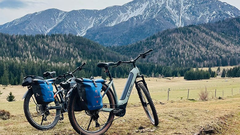 Two mountain bikes with blue bags in front of a mountain landscape in the Schneebergland.