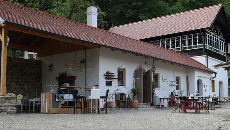 A traditional building with a red tiled roof and wooden elements, surrounded by trees.
