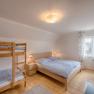Bright bedroom with double bed and bunk bed, wooden floor and window with curtains.